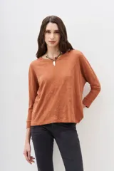 Remera de manga larga color terracota con textura jaspeada, confeccionada en algodón peruano. Presenta un calce holgado con mangas que se ensanchan debajo del brazo y se ajustan en la muñeca.