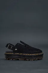 Mules negras de gamuza con plataforma gruesa y suela estriada con costura amarilla visible. Posee tira ajustable con hebilla metálica en el talón.