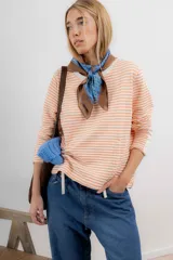 Remera de tejido de punto a rayas horizontales color naranja y blanco, de corte recto, cuello redondo y mangas largas.