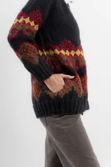 Saco de lana y poliamida color negro con diseño geométrico en tonos marrón, rojo y amarillo. Tiene silueta recta, largo debajo de la cola, bolsillos en los costados y escote polera con botones en todo el largo.