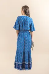 Vestido largo azul con estampado floral, escote en V, botones en el frente y volado en el ruedo.