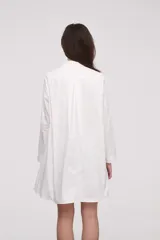 Camisa blanca de corte amplio con botones delanteros y manga larga.