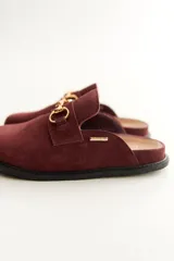 Mocasines tipo sueco de cuero gris con detalle de hebilla dorada.