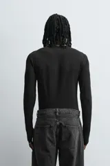 Camiseta de manga larga color crudo, corte ajustado y cuello redondo. Tiene aberturas en los puños y efecto lavado.