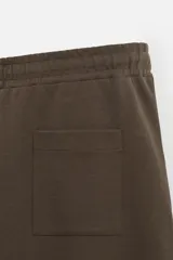 Pantalón negro de corte recto confeccionado en tejido interlock de algodón con elasticidad. Tiene cintura elástica ajustable con cordón, bolsillos frontales y bolsillos traseros de vivo.
