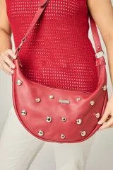 Cartera bandolera color rojo con apliques metálicos plateados.