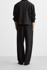 Pantalón negro de corte recto con cintura elástica, bolsillos laterales y un bolsillo trasero de ojal.