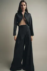 Pantalón de jean azul oscuro, de tiro muy alto y pierna ancha. Presenta pinzas en la parte delantera y cierre trasero con cremallera oculta.