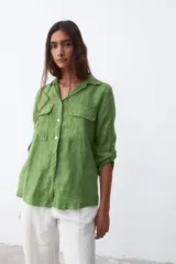 Camisa verde de lino con cuello clásico, cierre frontal con botones, mangas largas con trabilla para enrollar y dos bolsillos con solapa en el pecho.