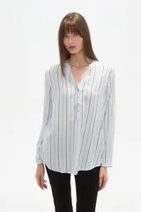 Blusa de viscosa con cuello mao y abertura frontal con botones. Presenta un estampado de rayas verticales finas en tonos azul claro, blanco, marrón y azul oscuro.