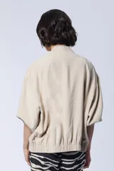 Campera bomber color beige con cierre frontal y mangas 3/4.