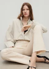 Jeans de tiro medio color beige, con cierre de cremallera y botón, trabillas, cinco bolsillos, bajo deshilachado y estilo flare. Confeccionados en tejido de algodón elástico.