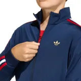 Campera deportiva Adidas Firebird de corte holgado, color azul marino con detalles en rojo y blanco en las mangas.