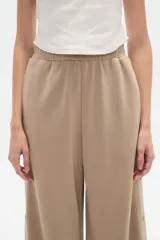 Pantalón deportivo negro de corte holgado, con cintura elástica, bolsillos laterales y botones a presión en las costuras laterales de las piernas.