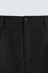 Pantalón de vestir negro de corte recto, con cintura elástica, pliegues frontales, bolsillos laterales y traseros.