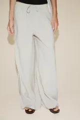 Pantalón palazzo color verde oliva de tejido fluido, tiro medio, cintura elástica ajustable con cordones y bolsillos laterales.