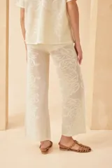 Pantalón tejido color crudo, con diseño calado de corazones y arabescos. Corte palazzo.