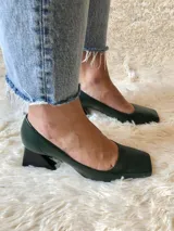 Zapato de cuero verde oscuro con punta cuadrada y tacón geométrico negro. Forro, capellada y plantilla 100% cuero. Tacón de 5 cm.