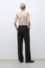 Pantalón de corte recto y tiro medio en color verde oliva, con cierre frontal de cremallera y botón, y bolsillos laterales.