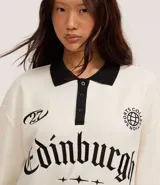 Saco blanco con cuello polo negro, confeccionado en algodón y poliéster. Presenta rayas en los puños y bajo, y estampa con la palabra "Edinburgh" en el pecho.
