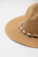 Sombrero de paja color beige con ala ancha y cinta decorativa con conchas y piedras de colores.