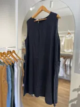 Vestido corto color beige de lino, con cuello redondo, sin mangas y bolsillos laterales.