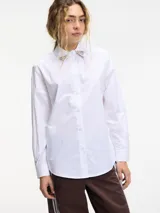 Camisa blanca de algodón con botones frontales y cuello camisero con apliques de pedrería.