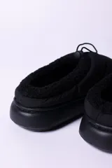 Pantuflas negras acolchadas con interior de piel sintética y ajuste con cordón elástico.