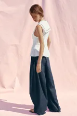 Top blanco de popelina con cuello marinero, escote pico, sin mangas y lazo negro en el frente.