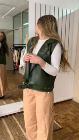 Chaleco verde de ecocuero con cuello solapa y cierre con botones a presión.