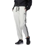 Pantalón deportivo New Balance Performance Fleece para mujer, color blanco, con cintura elástica, corte holgado y logo de la marca en la pierna izquierda. Presenta una banda lateral con la inscripción "New Balance" repetida en negro.