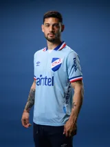 Camiseta de fútbol celeste con detalles en azul y rojo, escudo del Club Nacional de Football en el pecho y logos de Umbro y sponsors.