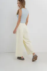 Pantalón 3/4 estilo palazzo confeccionado en denim liviano de tono amarillo pastel, tiro medio con pliegues delanteros, bolsillos delanteros y traseros aplicados, con detalle de logo metálico PEACH en la parte posterior.
