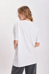 Remera blanca de corte amplio con estampa de un cowboy montando un caballo y la frase "Western Cowboy" en letras marrones y estilo cuerda. 