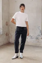 Pantalón de jean negro de corte mom, con apliques de tachas plateadas en la parte superior.