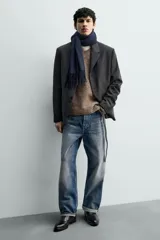 Bota de piel negra con punta fina, cierre de cremallera lateral y tacón bajo.