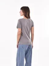 Remera negra de algodón con estampado frontal de la palabra "MERCI" en letras delineadas con colores del arcoíris.
