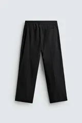 Pantalón negro de corte amplio confeccionado en tejido técnico, con cintura elástica, bolsillos delanteros y trasero de parche. Presenta bandas laterales a tono.