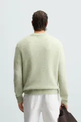 Sweater verde claro tejido con lana y alpaca, de corte regular, cuello redondo y manga larga con terminaciones en rib.