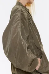 Gabardina corta de corte oversize, con cuello ajustable y cierre frontal de botones a presión.