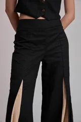 Pantalón ancho marrón con aberturas frontales que revelan un forro o panel interior de tela celeste. El pantalón se combina con un top a juego, creando un conjunto de dos piezas.