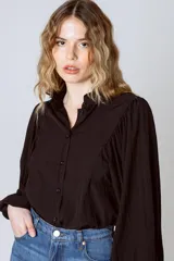 Camisa blanca de mangas largas abullonadas, con cuello mao y cierre frontal con botones.