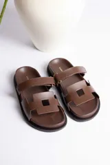 Sandalia plana color beige con dos tiras anchas en el empeine y suela negra.