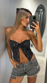 Top strapless negro con nudo central, confeccionado en tela con lentejuelas bordadas en forma de flor.