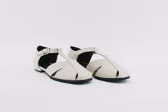 Zapatos bajos rojos de cuero, con puntera redondeada y tira central con hebilla. Presentan aberturas laterales.