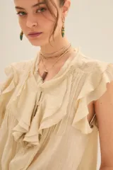 Camisa color crema de corte corto con escote redondo, mangas cortas con volados y jareta ajustable en el ruedo.