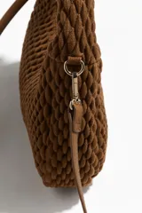 Cartera bandolera color marrón, con textura guateada, asa corta gruesa y correa fina extraíble. Cierre superior con cremallera y forro interior. Ancho 6 cm, alto 16 cm y largo 23 cm.