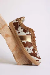 Zapatillas deportivas bajas con estampado animal print de vaca en blanco y marrón.