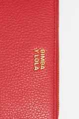 Billetera roja con exterior de piel y estructura rígida. Incluye cierre con cremallera, tirador de cordón, bolsillo interior con cierre de cremallera y logo grabado.
