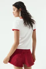 Remera blanca de algodón con cuello y mangas con ribete rojo. Estampado con cerezas y texto "Ibiza" en rojo.